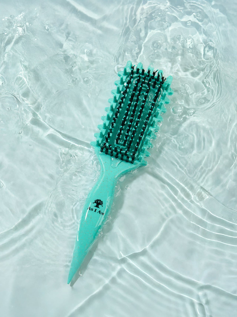 Brosse à cheveux turquoise avec poils noirs sur une surface blanche texturée