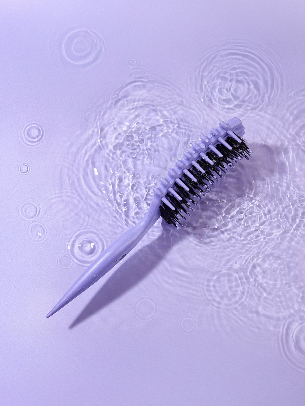 Brosse de nettoyage avec poils sur une surface texturée violette