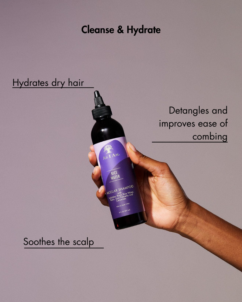 Main tenant un flacon de shampoing violet avec un texte sur les bienfaits des soins capillaires sur fond gris