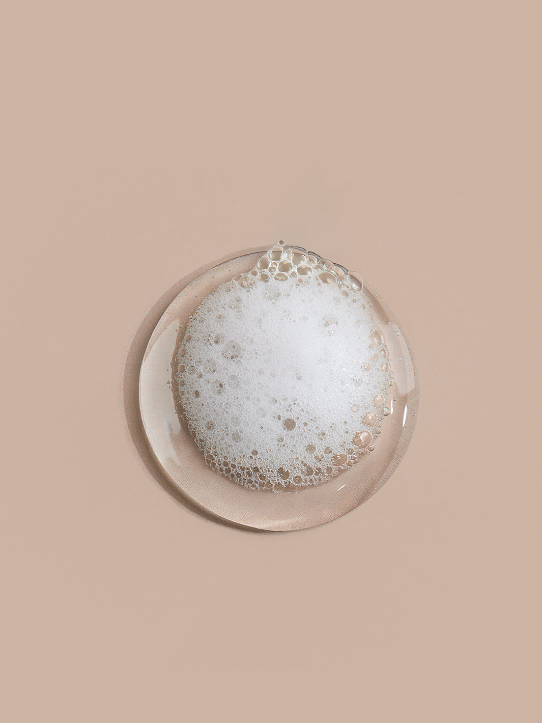 Plat rond en verre avec des bulles de savon sur fond beige