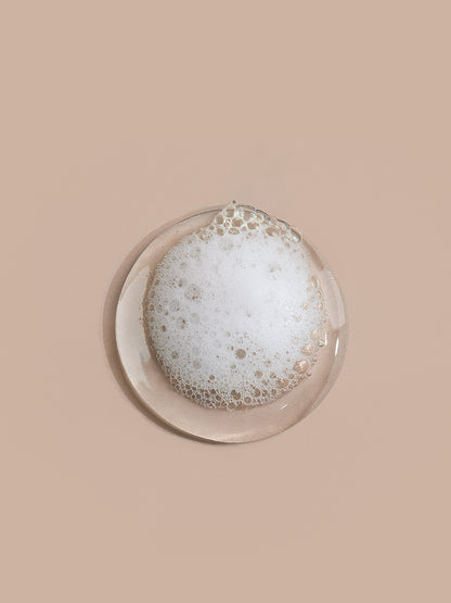 Plat rond en verre avec des bulles de savon sur fond beige