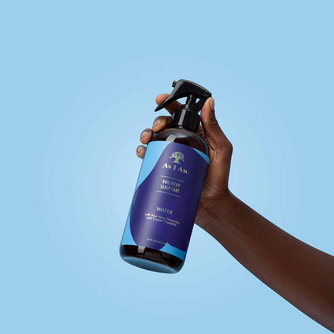 Main tenant un flacon de déodorant en spray AS I AM sur fond bleu clair