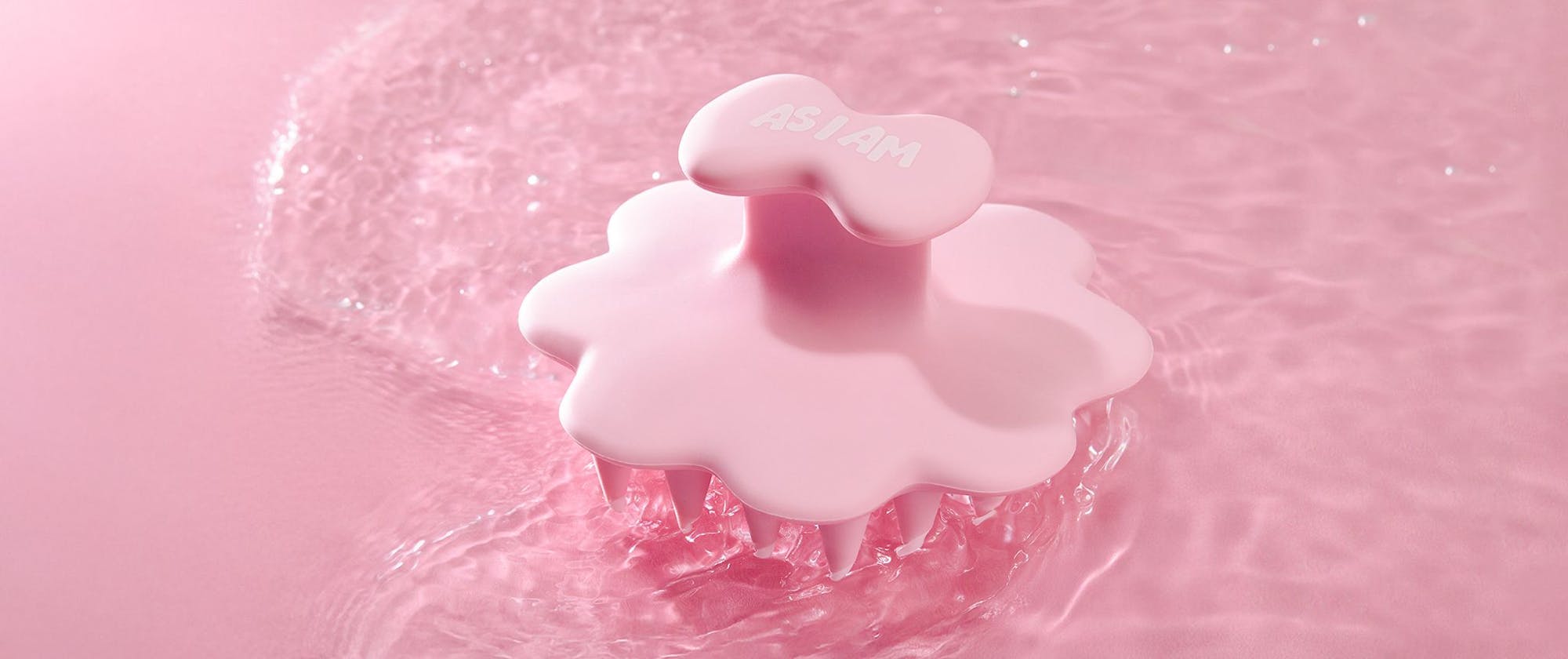 Brosse à cheveux rose avec gouttelettes d'eau sur fond rose