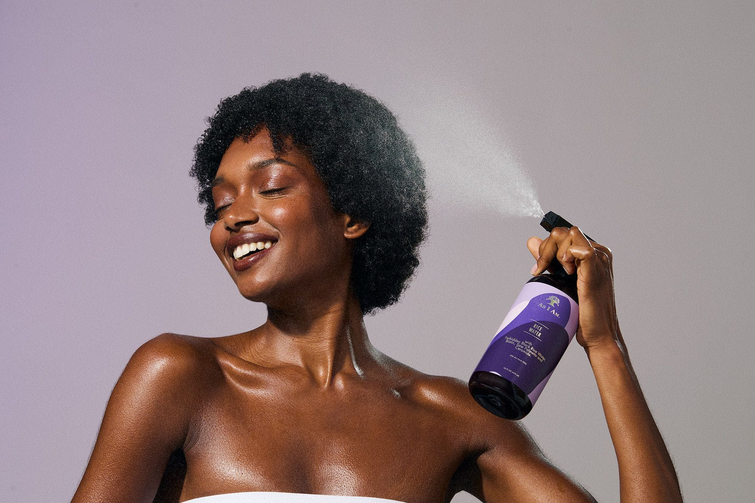 Femme appliquant un produit capillaire violet sur ses cheveux sur un fond uni