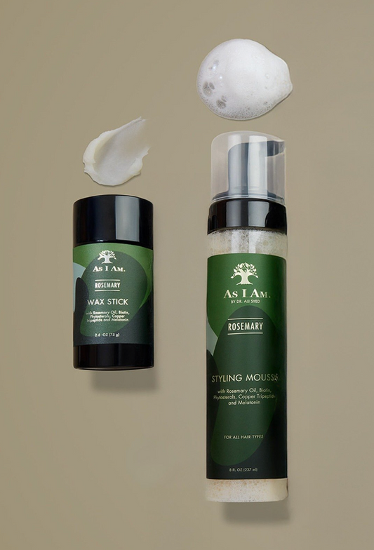 Produits de soins capillaires As I Am, notamment un stick de cire et une mousse coiffante, sur fond beige.